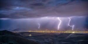 Lighting strikes over a city in a distant shot